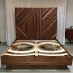 a bed with wooden headboard and foot board in a room next to a white curtain