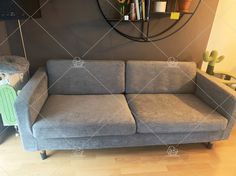 a grey couch sitting in front of a wall mounted clock