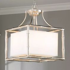 a chandelier hanging from the ceiling with white shades on it's lampshade