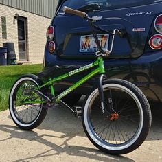 a green bike parked next to a blue car