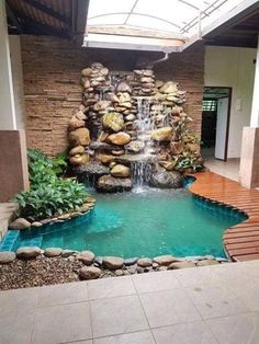 an indoor pool with waterfall and wooden steps leading up to the water feature in the center