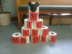 a stack of toilet paper with mickey mouse written on it and some other items in the background