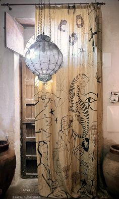 a bathroom with a shower curtain that has drawings on it and lights hanging from the ceiling