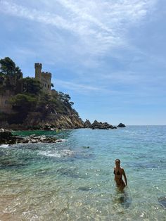 a man wading in the water near an island with a castle on it's side