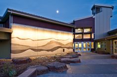 an outside view of a building at night with lights shining on the wall and steps leading up to it