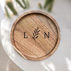 a wooden plate with the word ln on it and an olive branch in the center