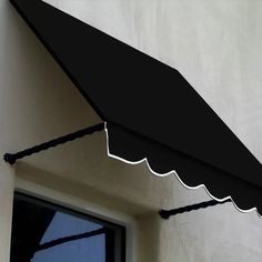 a black awning hanging from the side of a white wall next to a window