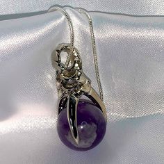 Pendant Made Of Amethyst Ball Held In A Silver Dragon Claw, Hanging In A Snake Silver Chain With Lobster Clasp. Silver Amethyst Jewelry For Healing, Silver Crystal Birthstone Necklace, Silver Amethyst Healing Jewelry, Silver Amethyst Birthstone Crystal Necklace, Silver Amethyst Necklace For Healing, Mystical Silver Amethyst Crystal Necklace, Spiritual Silver Amethyst Crystal Necklace, Mystical Silver Amethyst Necklaces, Silver Amethyst Pendant Crystal Necklace