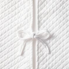 an unmade bed with white sheets and a bow on the top of it's edge