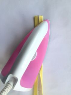 a pink and white hair dryer sitting on top of a yellow corded comb