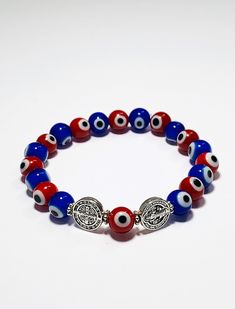 A protection bracelet fit for anyone! This bracelet comes blessed and ready to be use by the wearer. It has been elaborated with red and blue evil eye beads followed by 2 stainless steel St. Benedict charms, all strung together with high quality elastic making it super easy to put on! The Saint Benedict Medal is considered one of the most powerful symbols of protection. It is used for prayer against evil, for strength in a time of temptation, for peace among ourselves and the nations of the worl Symbolic Multicolor Round Beads Bracelets, Symbolic Multicolor Round Beads Bracelet, Handmade Red Symbolic Beaded Bracelets, Red Symbolic Handmade Bracelets, Symbolic Multicolor Bracelets As Gift, Adjustable Red Stretch Bracelet Spiritual Style, Red Spiritual Charm Bracelet, Blue 8mm Beads Wristband Gift, Blue Beaded Wristband Gift