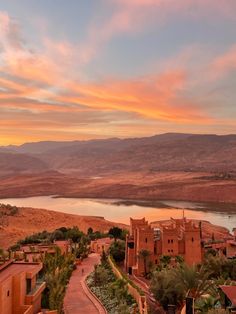 an aerial view of a desert town with mountains and water in the background at sunset