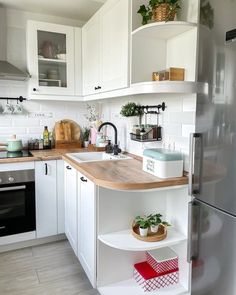 a kitchen with white cabinets and wooden counter tops, along with a stainless steel refrigerator