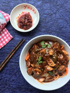 a bowl of food with chopsticks next to it on a blue table cloth