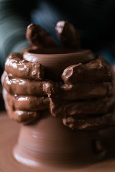 a potter's hands holding a clay pot with melted chocolate on it