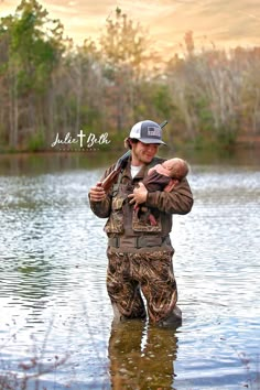 a man holding a baby in his arms while standing in the middle of a body of water