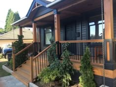 a porch with some plants on it and a swing in front of the house,