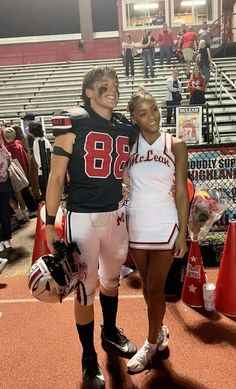 a couple of people that are standing in front of some bleachers at a football game