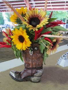 a cowboy boot with sunflowers and feathers in it