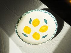 a white plate with yellow lemons painted on it