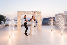 a bride and groom dancing on the dance floor with sparklers in the air at their wedding reception