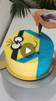 a person cutting into a cake decorated with cartoon characters on the top and bottom layer