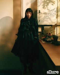 a woman standing next to a counter in a kitchen with sunlight coming through the window