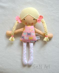 a doll with blonde hair and pink dress laying on top of a white sheeted surface