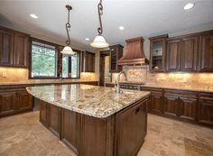 a large kitchen with marble counter tops and wooden cabinets