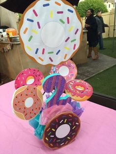 a table topped with lots of doughnuts on top of a pink table cloth