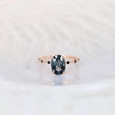 an oval cut black diamond sits on a white surface