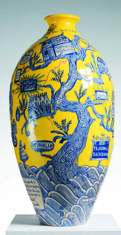 a yellow and blue vase sitting on top of a white table next to a wall