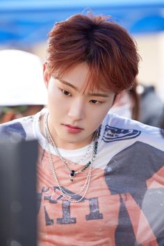 the young man is looking at his cellphone while wearing an orange and white shirt