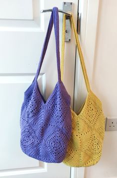 two crocheted purses hanging on a door handle, one in yellow and the other in purple