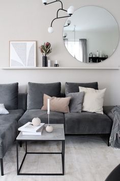 a living room filled with furniture and a large mirror above the sectional couch, next to a coffee table