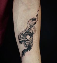 a man's arm with a black and white tattoo design on the left forearm