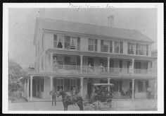 an old black and white photo of a horse drawn carriage in front of a large house