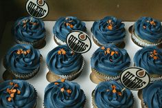 cupcakes with blue frosting and orange sprinkles in a box