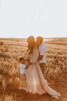 a man and woman are standing in the middle of a field with their baby boy