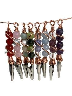 several different types of beads hanging from a line on a white background with copper wire