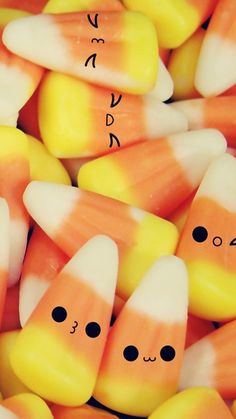 there are many candy corn with faces drawn on the top one is orange and white