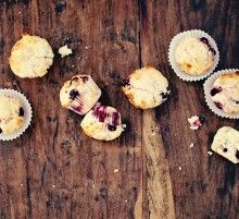 several muffins on a wooden table with one broken in half