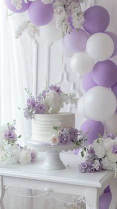 a white cake sitting on top of a table next to purple and white balloons