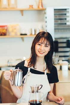 a woman in an apron holding a coffee pot