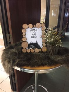 a welcome wild things sign sitting on top of a stool