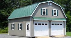 two garages with green roof and white doors on gravel road in front of trees