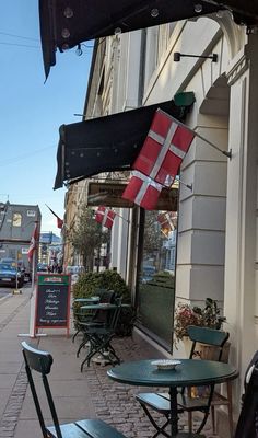 the outside of a restaurant with tables and chairs on the side walk next to it