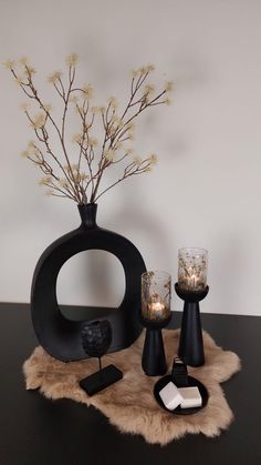 a table topped with candles and vases on top of a wooden table next to a wall