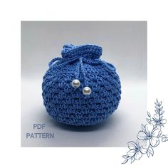 a crocheted blue ball with a bow on it's side and pearls in the middle