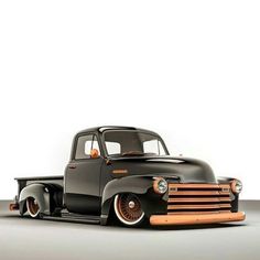 an old black pickup truck parked on top of a gray floor next to a white wall